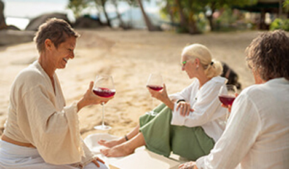 Friends celebrating on a beach at dusk with wine glasses