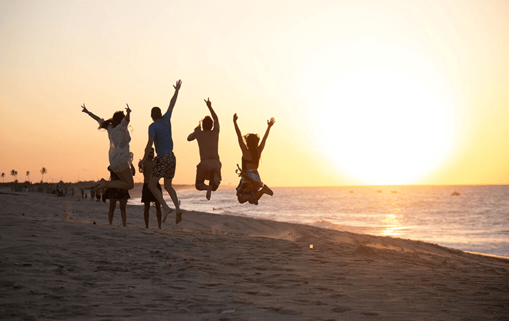 Friends celebrating together on a beach at sunset